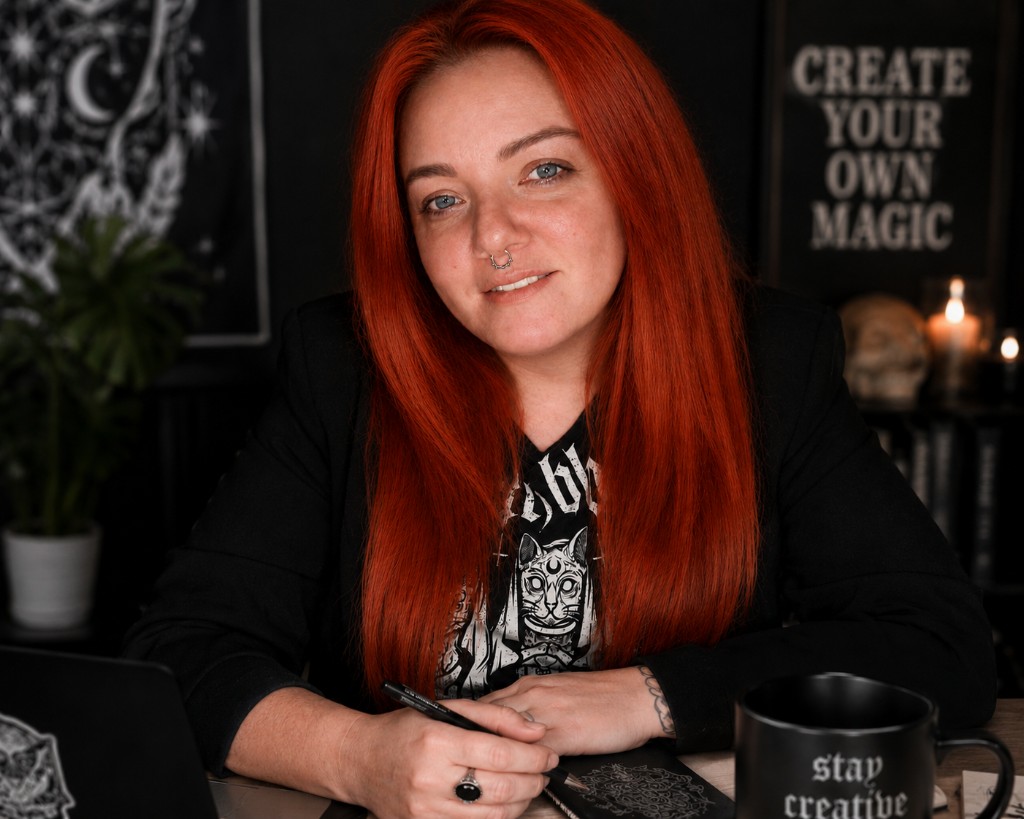 Arsay an ihrem Schreibtisch, rote Haare, schwarzes Shirt